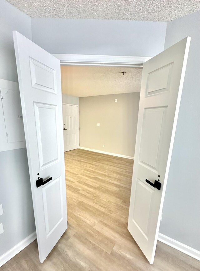 corridor featuring a textured ceiling and light hardwood / wood-style flooring