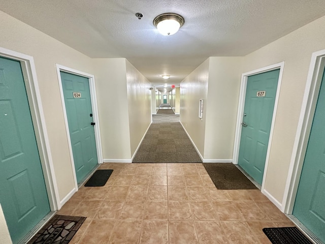 corridor with a textured ceiling and light tile patterned flooring