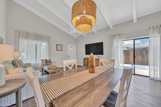 dining room with hardwood / wood-style flooring, ceiling fan with notable chandelier, beamed ceiling, and high vaulted ceiling