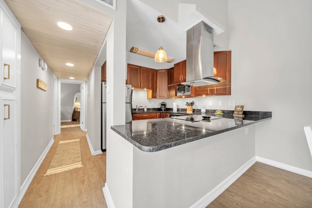 kitchen with pendant lighting, island range hood, light wood-type flooring, white fridge, and kitchen peninsula