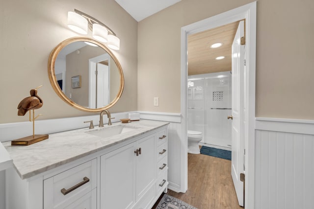 bathroom with hardwood / wood-style floors, vanity, an enclosed shower, and toilet