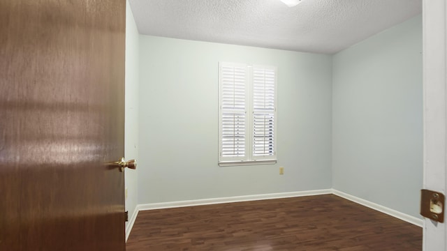 empty room featuring a textured ceiling, baseboards, and wood finished floors