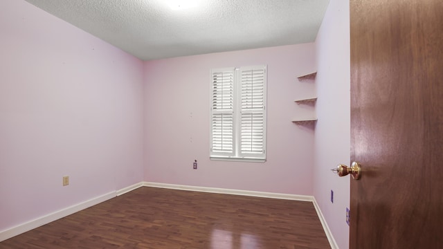 unfurnished room with dark wood-style floors, a textured ceiling, and baseboards