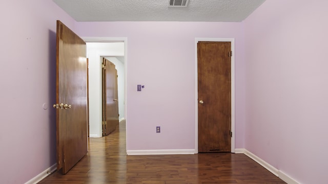 unfurnished bedroom with visible vents, a textured ceiling, baseboards, and wood finished floors