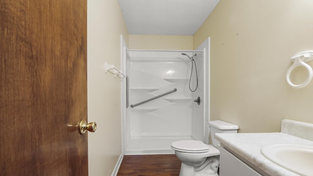 full bath with toilet, wood finished floors, walk in shower, a textured ceiling, and vanity