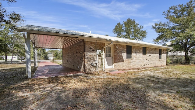 single story home featuring metal roof, a carport, and brick siding