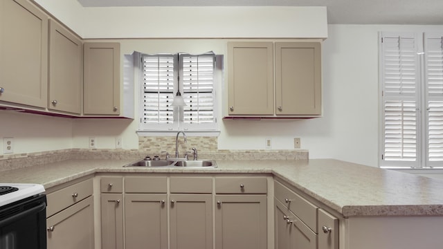 kitchen with a peninsula, electric range, a sink, and light countertops