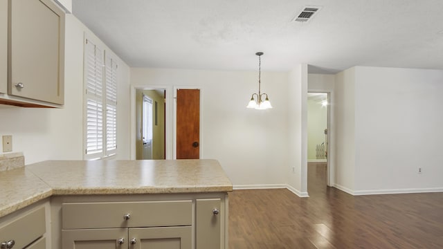 kitchen featuring light countertops, visible vents, dark wood-type flooring, a peninsula, and baseboards