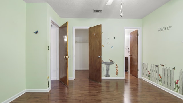 interior space with a textured ceiling, wood finished floors, visible vents, and baseboards