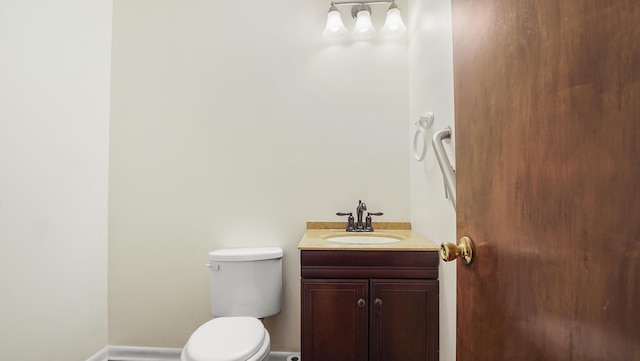 bathroom with baseboards, vanity, and toilet