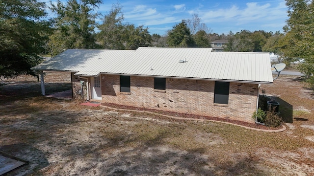 back of property featuring brick siding and metal roof