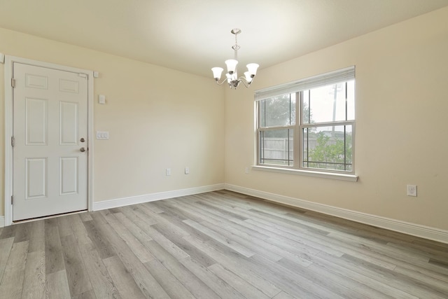 empty room with light hardwood / wood-style flooring and a chandelier