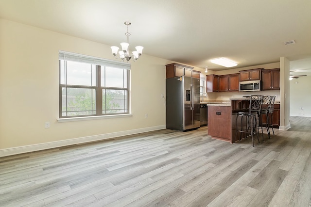 kitchen featuring a center island, hanging light fixtures, stainless steel appliances, a breakfast bar, and light wood-type flooring