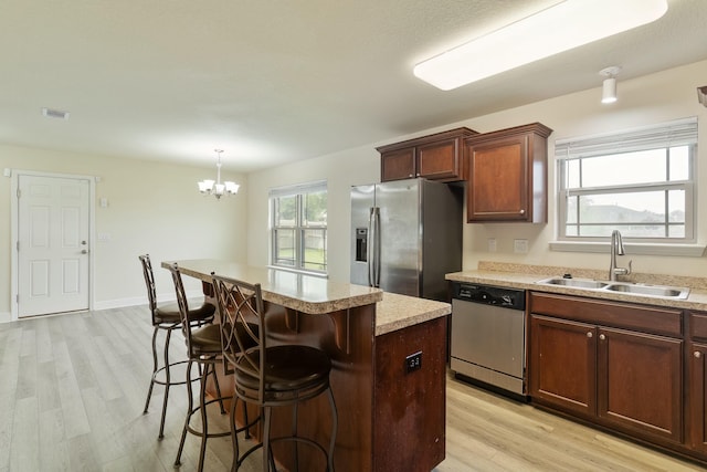 kitchen with sink, a center island, stainless steel appliances, and light hardwood / wood-style flooring