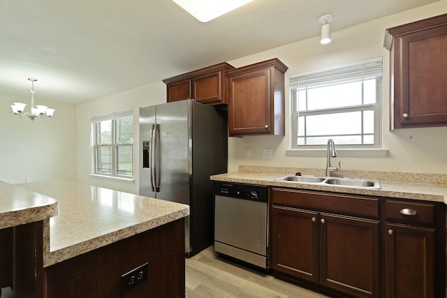 kitchen with appliances with stainless steel finishes, light hardwood / wood-style floors, an inviting chandelier, and plenty of natural light