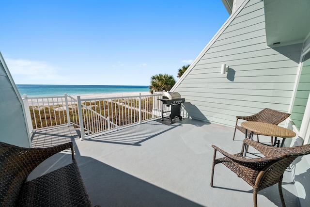 balcony with a water view, grilling area, and a view of the beach