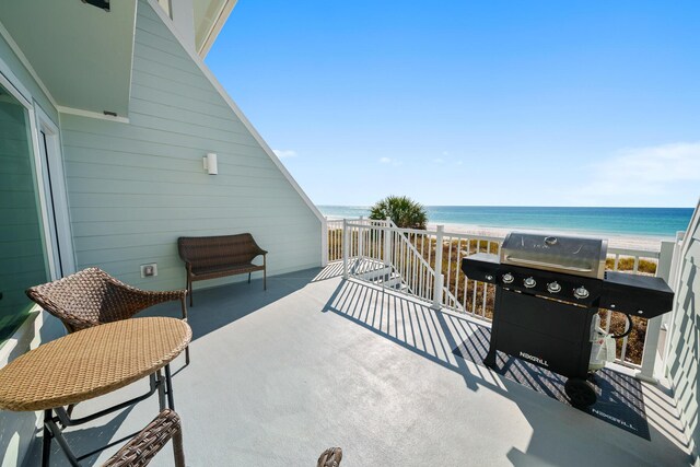 view of patio / terrace featuring a balcony, a water view, and a beach view