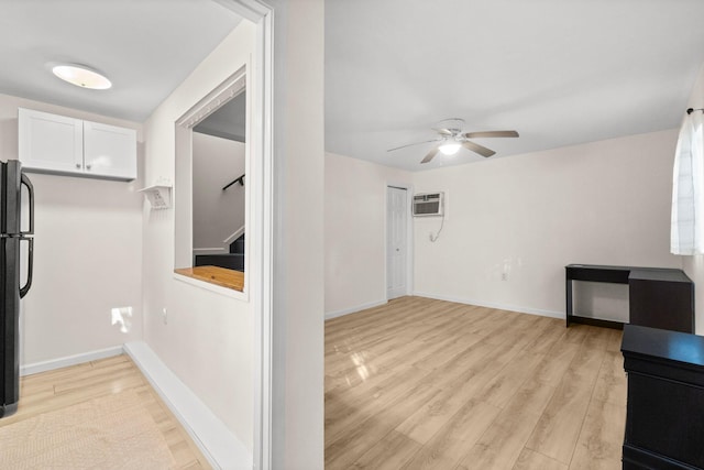 interior space with ceiling fan, a wall mounted AC, and light hardwood / wood-style flooring