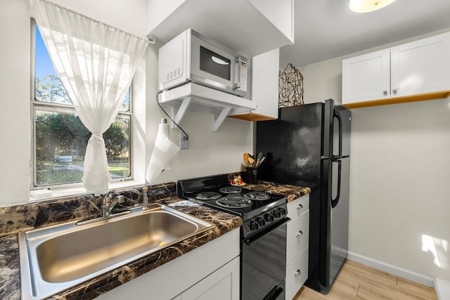 kitchen featuring sink, black range with gas stovetop, white cabinetry, and light wood-type flooring