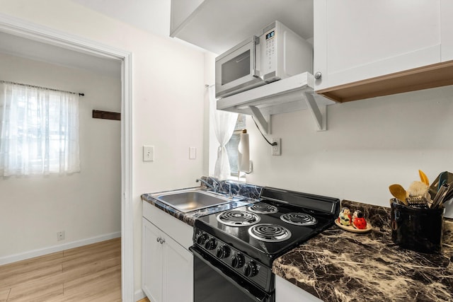 kitchen featuring white cabinets, light wood-type flooring, black range oven, and sink