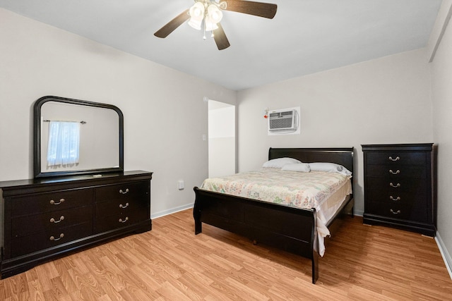 bedroom featuring a wall mounted air conditioner, light wood-type flooring, and ceiling fan