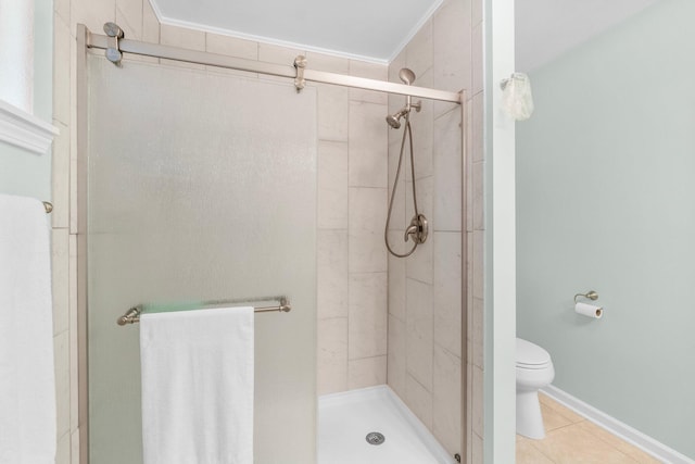 bathroom with tile patterned floors, a shower with shower door, toilet, and ornamental molding