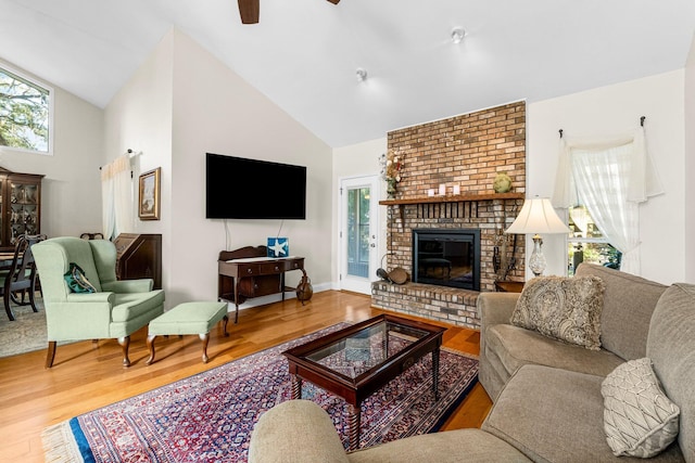 living room featuring hardwood / wood-style floors, ceiling fan, high vaulted ceiling, and a brick fireplace