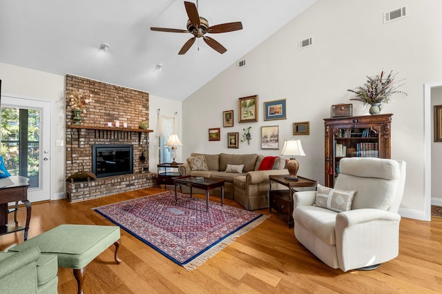 living room featuring ceiling fan, wood-type flooring, a fireplace, and high vaulted ceiling