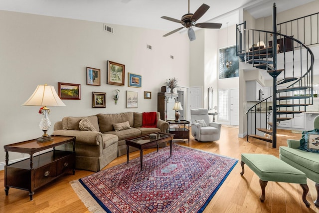 living room featuring ceiling fan, light wood-type flooring, and high vaulted ceiling