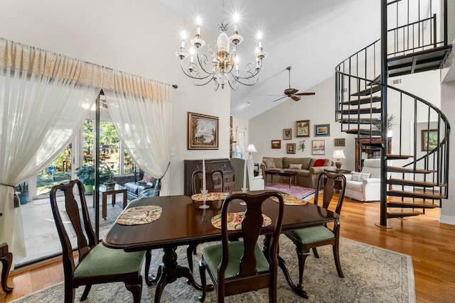 dining area with wood-type flooring, ceiling fan with notable chandelier, and high vaulted ceiling