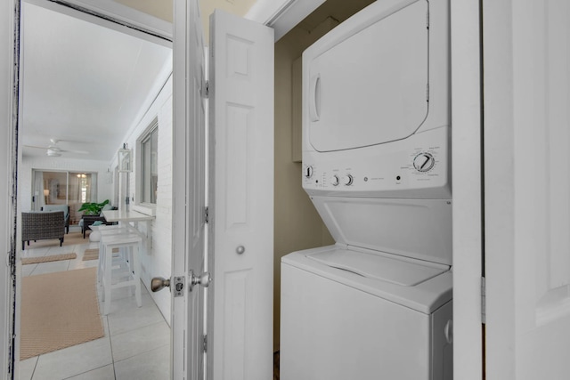 laundry room with ceiling fan, light tile patterned floors, and stacked washer and dryer