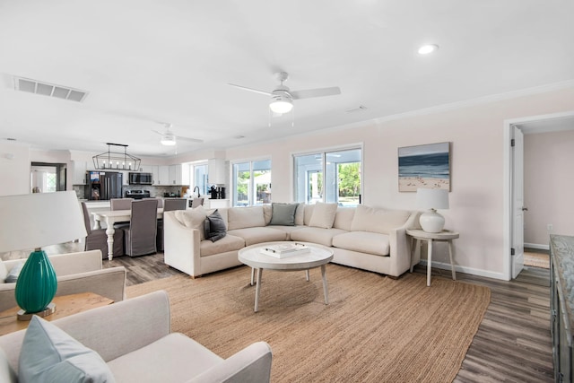 living room featuring ceiling fan with notable chandelier, hardwood / wood-style flooring, and crown molding