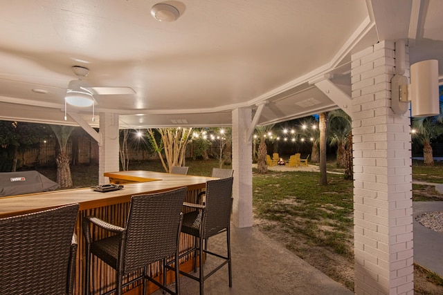 patio at night featuring area for grilling and a bar