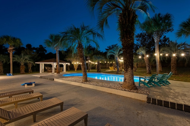 pool at twilight featuring a patio area