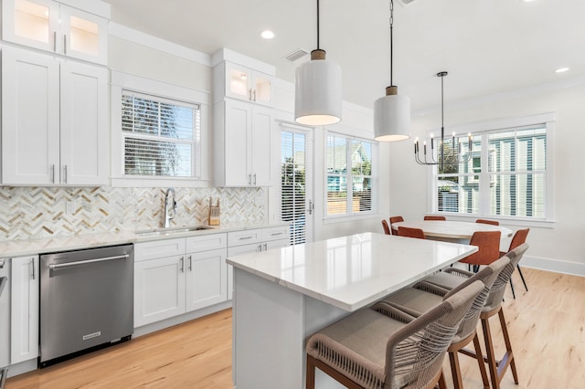 kitchen featuring pendant lighting, sink, white cabinets, and stainless steel dishwasher