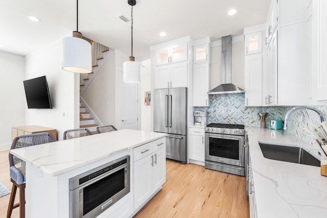 kitchen featuring a center island, white cabinetry, wall chimney range hood, and stainless steel appliances