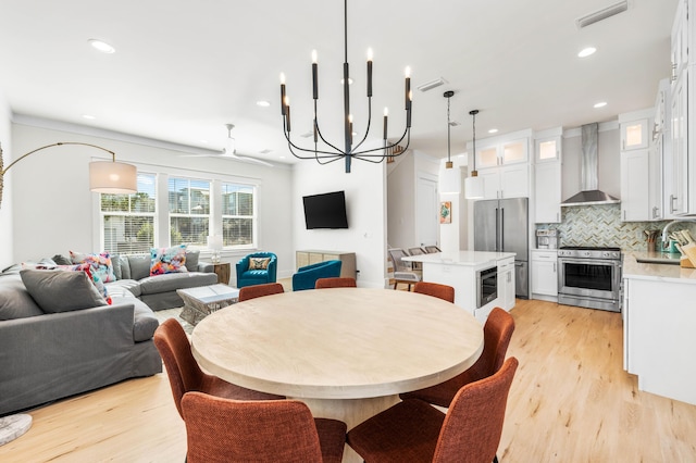 dining area featuring sink, light hardwood / wood-style flooring, and a chandelier