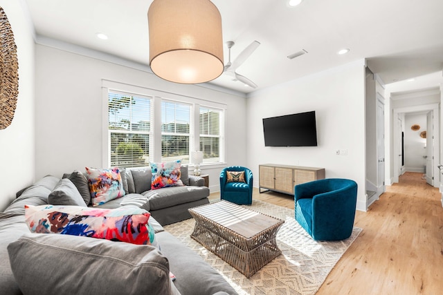 living room featuring ceiling fan, ornamental molding, and light wood-type flooring