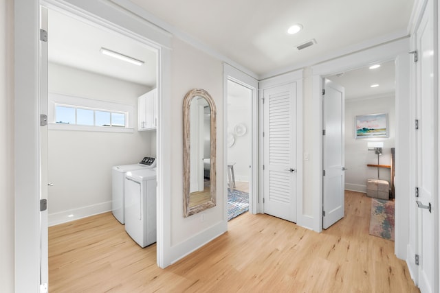 clothes washing area featuring washer and clothes dryer, light hardwood / wood-style flooring, and cabinets