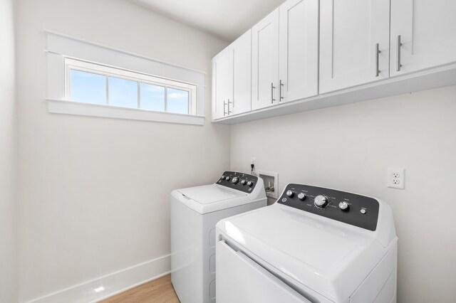 clothes washing area featuring washer and dryer, cabinets, and light hardwood / wood-style flooring