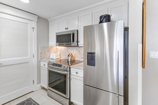 kitchen with light stone countertops, appliances with stainless steel finishes, tasteful backsplash, white cabinetry, and light tile patterned flooring