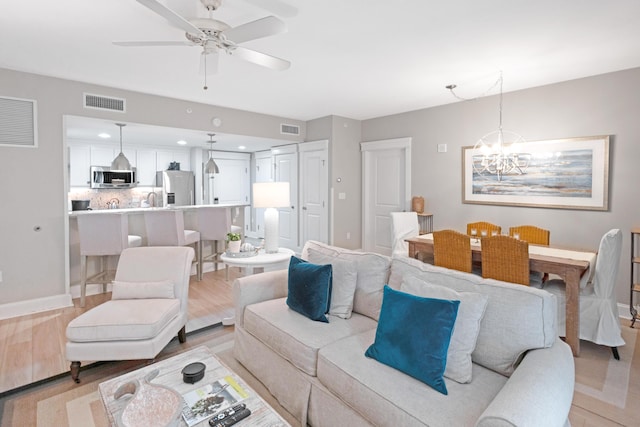 living room featuring light hardwood / wood-style flooring and ceiling fan with notable chandelier