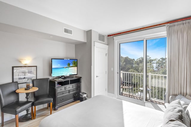 bedroom featuring access to exterior, light wood-type flooring, and multiple windows