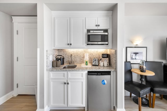 kitchen with sink, white cabinets, light wood-type flooring, and appliances with stainless steel finishes