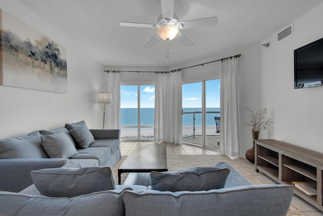 living room featuring ceiling fan, light tile patterned floors, and a textured ceiling