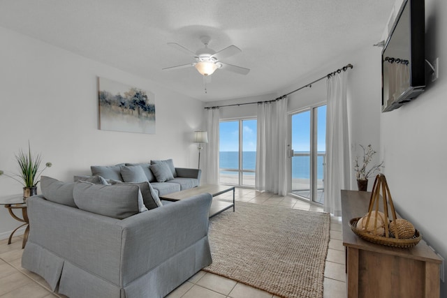 living room featuring light tile patterned floors, a textured ceiling, a water view, and ceiling fan