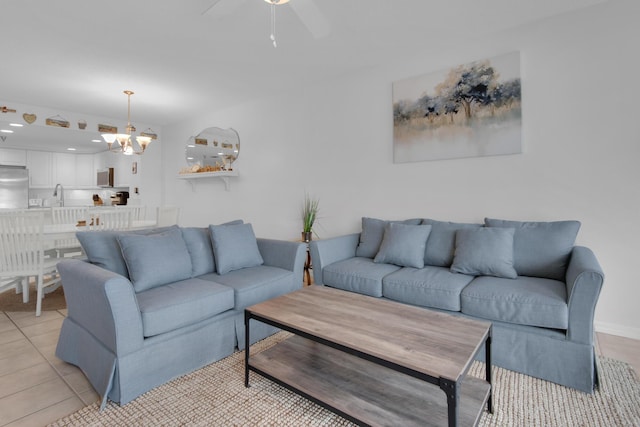 living room with ceiling fan with notable chandelier, light tile patterned floors, and sink