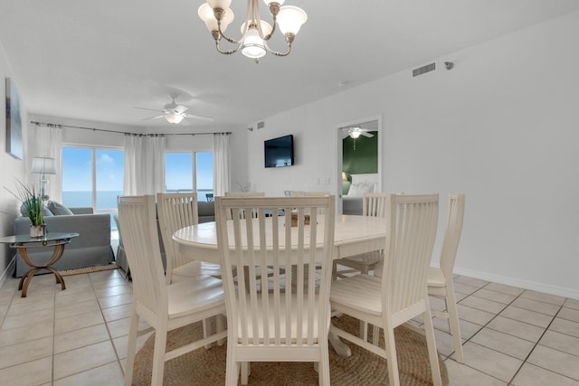 tiled dining area with a water view and ceiling fan with notable chandelier