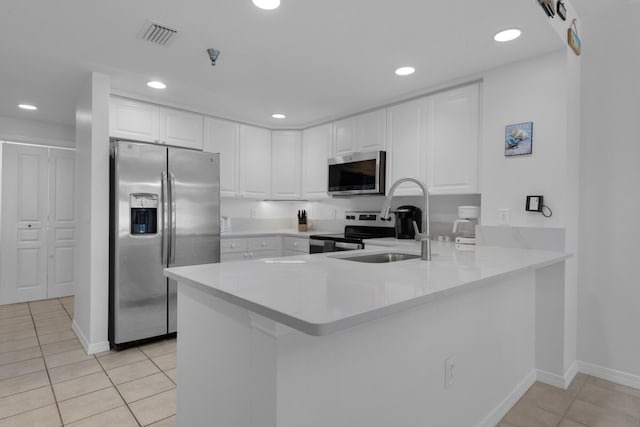 kitchen featuring kitchen peninsula, light tile patterned flooring, white cabinets, and stainless steel appliances