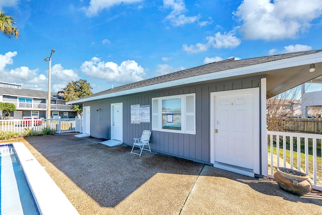 back of property featuring a patio, a shingled roof, board and batten siding, and fence